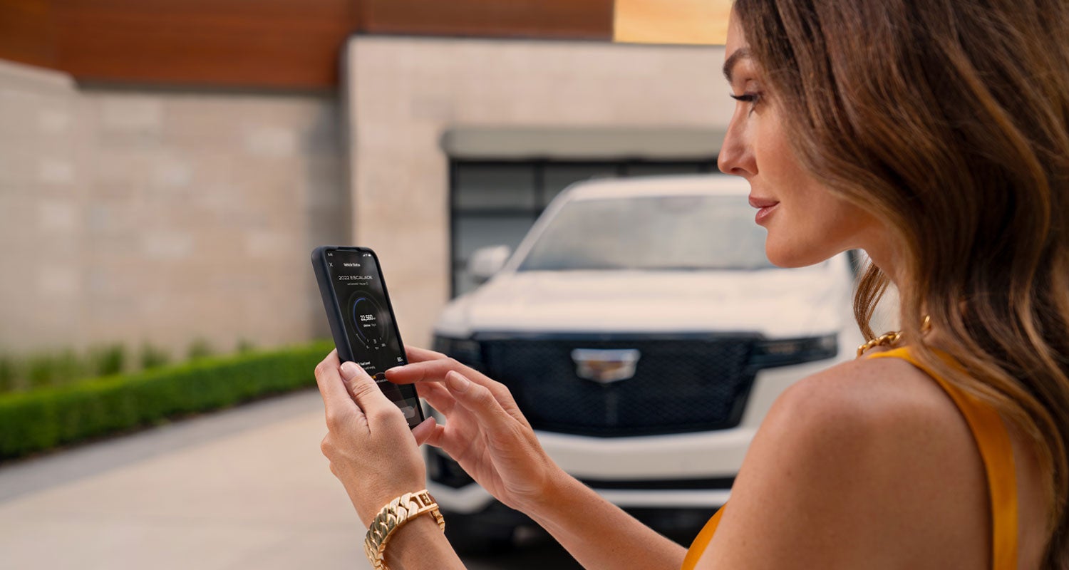 lady checking her mobile with a Cadillac vehicle background | Lima Cadillac in LIMA OH
